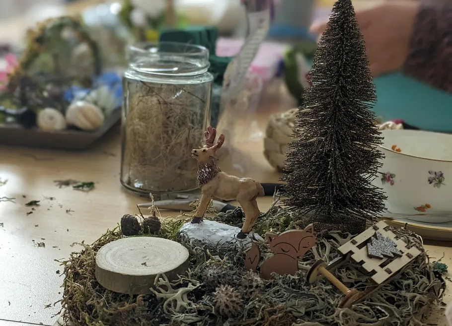 A deer stands on moss surrounded by decorations.