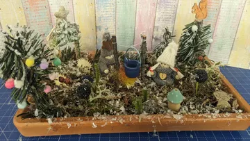 Kreatives Miniatur-Arrangement mit Figuren und Pflanzen in Schnee.