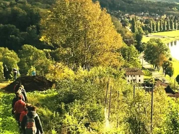 Hikers walk along a slope surrounded by nature.