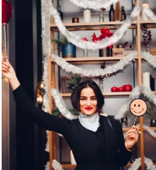 Woman with lollipop and smiley sign celebrating in front of decoration.