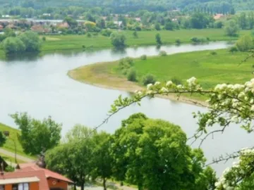 River flows through a green, hilly landscape.
