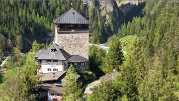 Steinernen Turm steht zwischen Bäumen in bergiger Umgebung.
