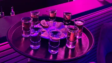 Tray of shot glasses with lime wedges in a bar.