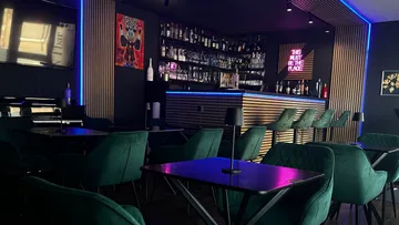 Elegant bar interior with a long drinks wall and tables.