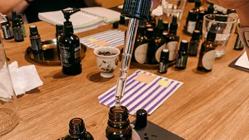 Pipette entnimmt Flüssigkeit aus einer dunklen Flasche auf Tisch.