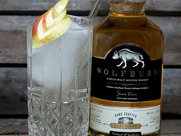 Glas mit Eis und Whisky, dekoriert mit Apfelscheibe.