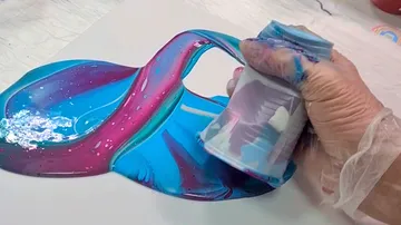 Hand pouring colorful paint onto canvas