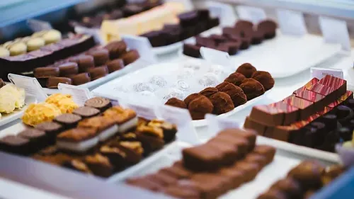 Types of chocolate lie on plates in a display case.
