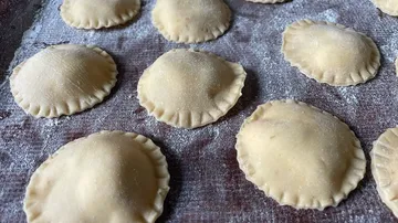 Teigtaschen liegen auf bemehltem Untergrund, bereit zum Kochen.