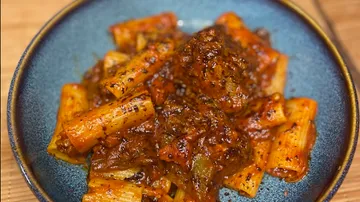 Rigatoni with rich tomato meat sauce in bowl.