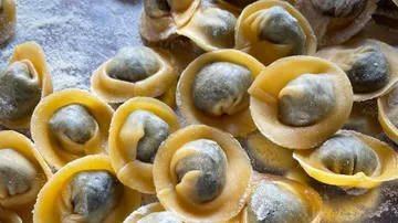 Heap of filled dumplings on a floured table.