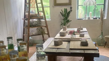 Wooden table with pieces of clay and flower vase in a creative space.