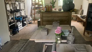 Holztische mit Ton und Blumen in einem gemütlichen Raum.