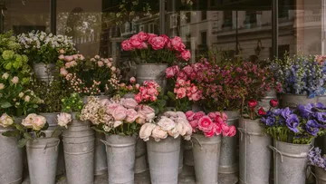 Assorted flowers in metal buckets outside shop.