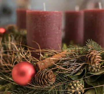 Red candles with pine cones and ornament.