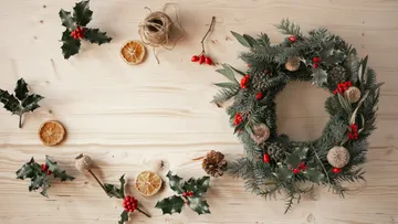 Festive wreath surrounded by holly and dried oranges.