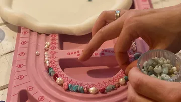 Perlen werden auf einer rosa Perlenplatte angeordnet.