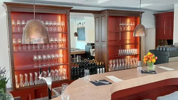 Elegante Bar mit Gläsern, Flaschen und frischen Blumen.