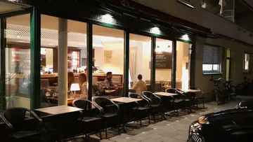 Restaurant mit Tischen, Gäste essen und unterhalten sich drinnen.