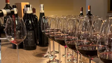 Gläser mit Rotwein werden von Flasche eingefüllt, elegant arrangiert.