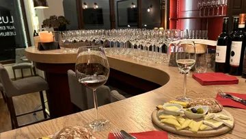 Rotwein und Weißwein stehen auf einem Tisch mit Käseplatte.