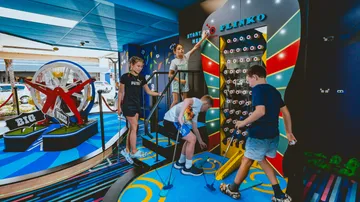 Children play on play equipment in a colorful interior.