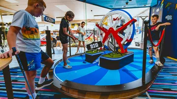 Four children play mini golf in a colorful leisure area.