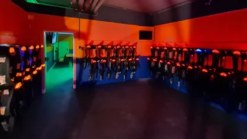 Laser tag equipment hangs on walls in dark rooms.