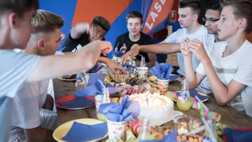 Young people celebrate their birthday, eat cake and drink drinks.