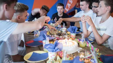Young men eat and party at a set table.