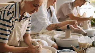 People crafting pottery on pottery wheels indoors.