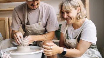 Two people using a pottery wheel together.
