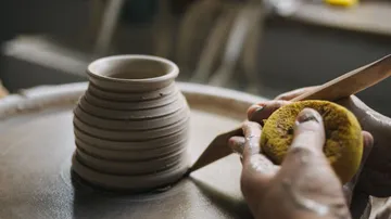 Hands shaping pottery on spinning wheel