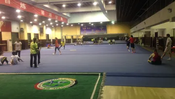 Sportler trainieren in einer großen, blauen Sporthalle.