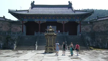 A golden lantern stands while four people walk in.