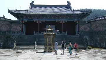 Temple with steps, tourists approach a lantern.