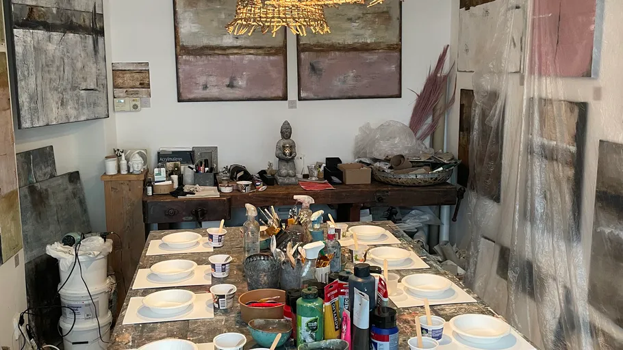 A table with paints and tools in a studio.