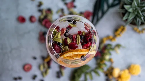 Glass with fresh fruits and herbs on table.