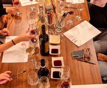 Glasses with wine are standing on a table, painting hands.