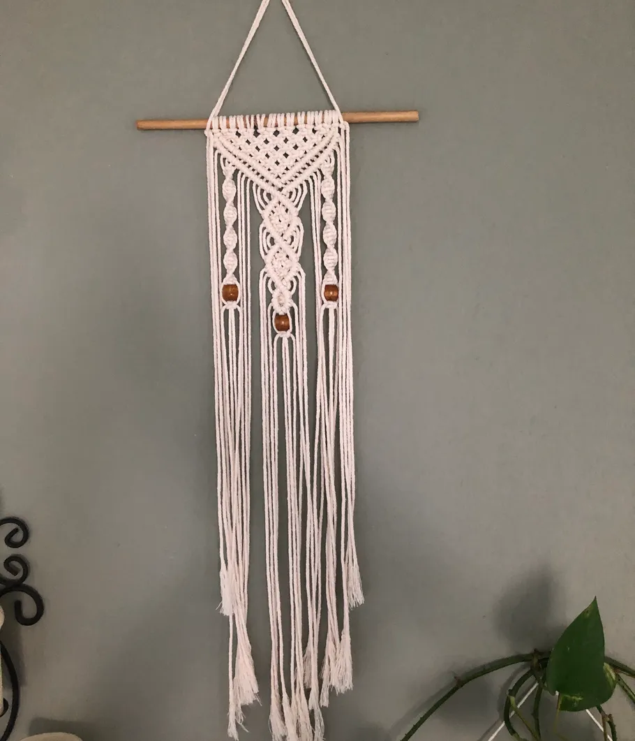 Macrame wall hanging on a pole on the wall.
