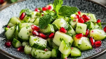 Frischer Salat mit Gurken, Granatapfel und Minze in Schüssel.