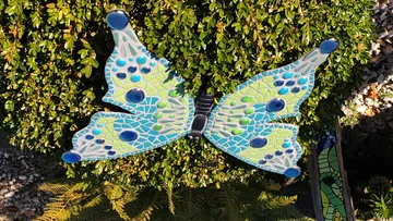 Bunte Mosaik-Schmetterling sitzt auf einem grünen Busch.