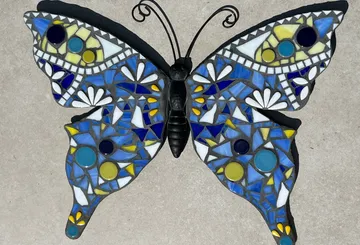 Bunte Schmetterlingsfigur aus Mosaik auf hellem Untergrund.