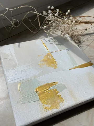 Abstract painting with gold accents, dried flowers nearby.
