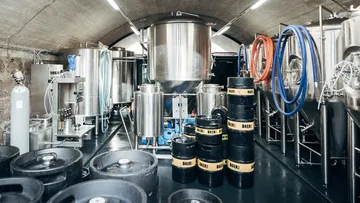 Brewery with tanks and barrels in a cool, industrial space.