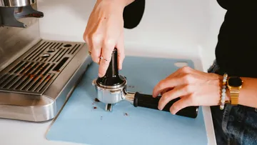 Hands squeeze a coffee plug on a work surface.