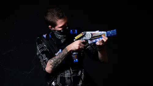 Person, die auf eine Lasertag-Pistole in einen dunklen Bereich zielt.