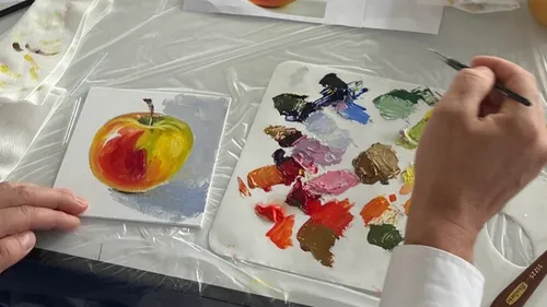 Künstler malt Apfel auf kleiner Leinwand.