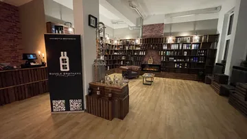 A sales room with shelves, bottles and a sofa.