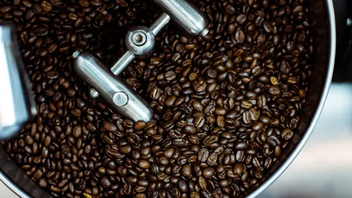 Coffee beans are roasted in a metal roaster.